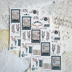 Op de afbeelding: Vellen tarot-thema stickers met illustraties van de kaarten "De Maan" en "De Geliefden", en andere mystieke ontwerpen. De stickers hebben een vintage esthetiek met zachte kleuren, waaronder beige, blauw en bruin. De tekst "Boojie#1424" is afgedrukt.
