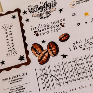 May include: A sheet of coffee-themed stickers with various designs. Includes coffee beans, stars, and phrases like "finding peace between two sips." The stickers are in shades of brown, black, and white.