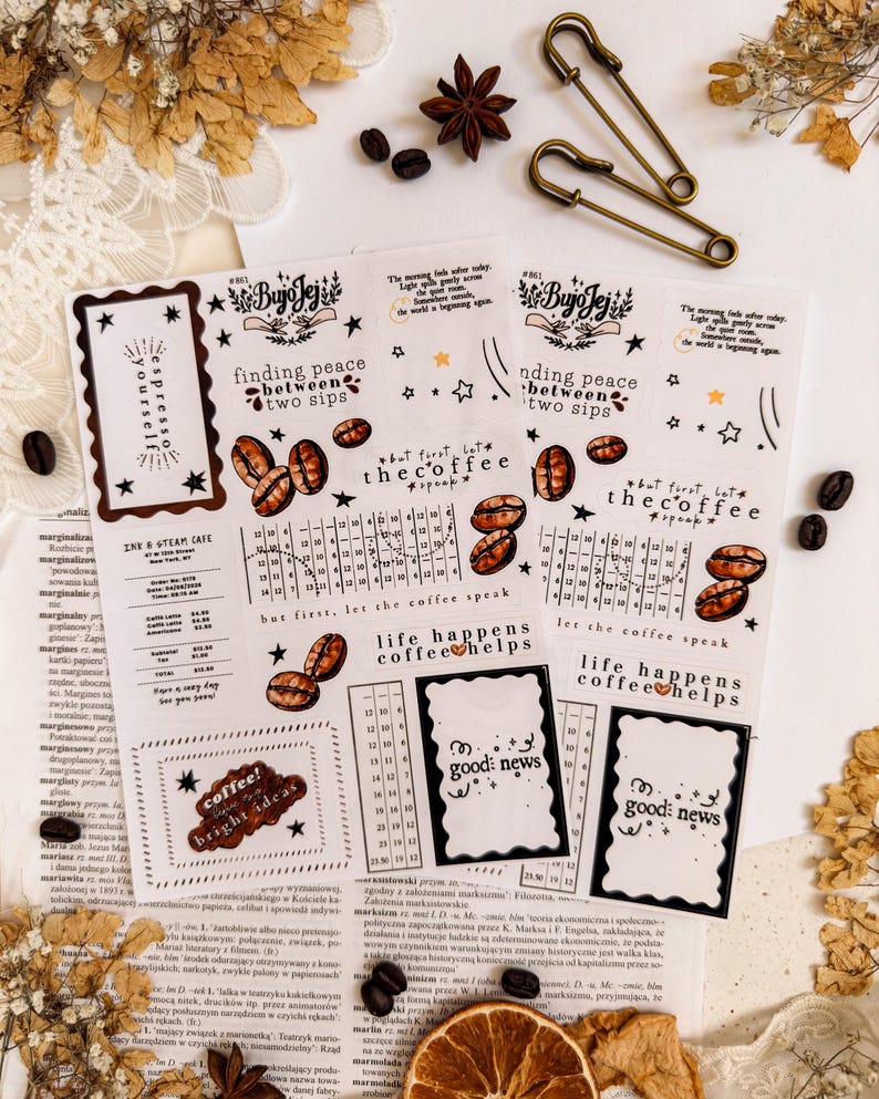 May include: A collection of coffee-themed stickers with various designs and text, including coffee beans, stars, and phrases like "finding peace between two sips" and "life happens coffee helps." Also, two antique brass safety pins and coffee beans.