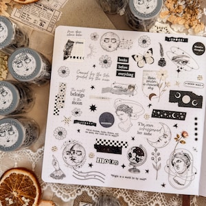 Könnte beinhalten: Eine Sammlung dekorativer Washi-Tape-Rollen und Aufkleber mit himmlischen und botanischen Designs. Die Klebebandrollen zeigen ein Gesicht mit einem Mondkranz. Die Aufkleber zeigen Monde, Sterne, Blumen und Text.