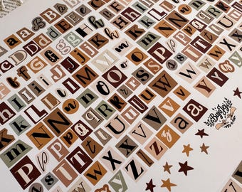 Puede incluir: Una hoja de pegatinas de alfabeto en varias fuentes y colores, incluyendo marrón, beige y verde. Las letras están dispuestas en un patrón de cuadrícula, con algunas pegatinas en forma de estrella. Ideal para scrapbooking y manualidades.