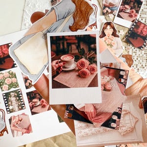 A hand holding several aesthetic cut-out stickers, including Polaroid-style images of coffee and roses, film strip frames, soft pink textures, and cozy lifestyle scenes. The background shows more stickers and the edge of the sticker sheet.