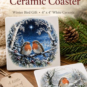 May include: Two square white ceramic coasters featuring a detailed illustration of two robins perched on a snowy branch under a starry night sky, with text reading Robin Redbreast Ceramic Coaster, Winter Bird Gift, and 4 inch by 4 inch.