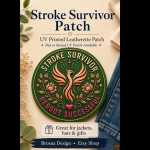 Può includere: Una toppa circolare in similpelle verde con una fenice color rame sopra un cuore rosa. Il testo recita STROKE SURVIVOR e REBOOT SUCCESSFUL. La toppa è stampata UV con una finitura in rilievo, adatta per essere applicata su giacche o cappelli.