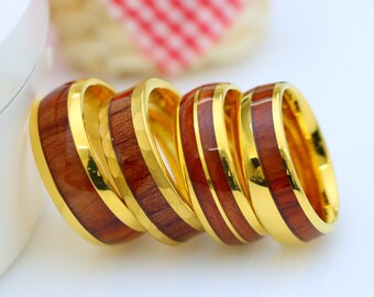 May include: Five gold rings with a wooden inlay. The rings are stacked on top of each other.