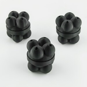 May include: Three black, spherical objects with a unique design. Each object is made up of multiple spheres clustered together and held by a band. The objects are arranged on a white surface.