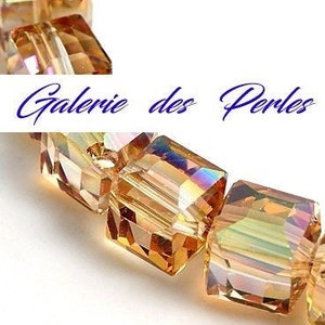 Peut inclure: Un brin de perles de cristal de couleur ambre, chaque perle est de forme carrée avec des facettes. Les perles sont enfilées sur un fil transparent. L'image est intitulée "Galerie des Perles".