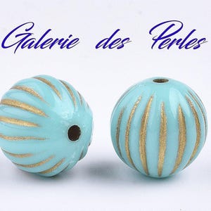 May include: Two turquoise blue round beads with gold stripes. The beads have a hole in the centre for stringing.