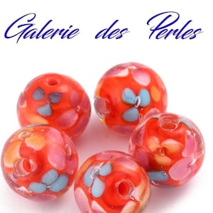 May include: Six red glass beads with a floral pattern in shades of pink, blue and yellow. The beads have a hole in the centre for stringing.