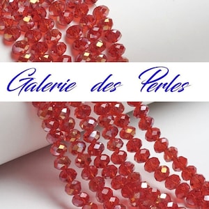 May include: A strand of red faceted glass beads. The beads are round and have a slight iridescent sheen. The beads are strung on a clear thread.
