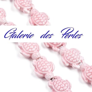 Peut inclure: Un brin de perles en céramique de tortue rose. Les perles sont enfilées sur un cordon blanc. Les perles sont toutes de la même taille et de la même forme. Les perles sont toutes orientées dans la même direction. Les perles sont toutes nettes. L'arrière-plan est blanc.
