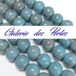Peut inclure: Un brin de perles en céramique bleu turquoise avec une texture mouchetée. Les perles sont rondes et ont une surface légèrement irrégulière.