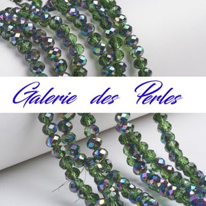 May include: A strand of iridescent green faceted glass beads. The beads are strung on a clear thread and are arranged in a row. The beads are about 6mm in diameter.