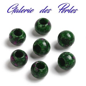May include: Seven green and purple gemstone beads with a hole through the center. The beads are round and have a mottled appearance.