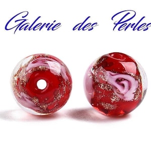 Peut inclure: Deux perles en verre rouge avec des accents dorés et blancs. Les perles ont un trou au centre pour être enfilées.