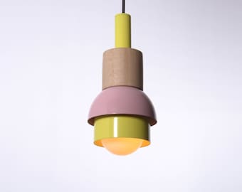Può includere: Una lampada a sospensione gialla, rosa e legno con una lampadina rotonda bianca.
