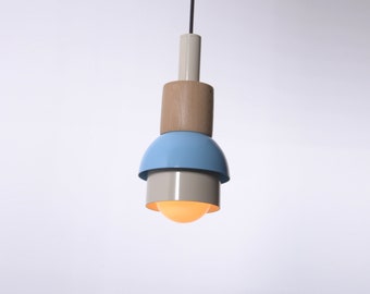 Può includere: Una lampada a sospensione con base in legno, un paralume blu chiaro e un paralume interno bianco.