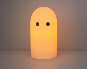 Può includere: Una luce notturna a forma di fantasma, di colore giallo tenue. La lampada presenta una parte superiore arrotondata e due occhi neri a forma di punti. Emette una calda luce, adatta per la cameretta di un bambino o come elemento decorativo.