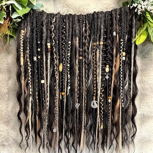 May include: A collection of black, dark brown, and blonde synthetic hair extensions featuring various textures including dreadlocks, twists, and braids. The strands are adorned with metallic beads, charms, and decorative thread wraps throughout the length.