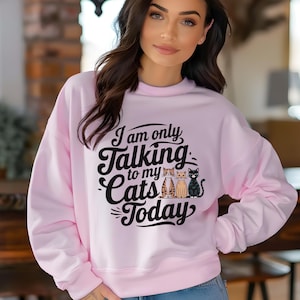 Może przedstawiać: Różowa bluza z czarnym nadrukiem, na którym widnieje napis "Rozmawiam tylko z moimi kotami dzisiaj" z trzema kreskówkowymi kotami na nadruku.