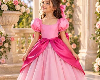 Puede incluir: Un vestido largo hasta el suelo con un corpiño rosa claro, mangas cortas abullonadas y escote cuadrado. La falda está superpuesta con tul rosa claro y acentuada por una sobrefalda de satén fucsia vibrante, un fajín a juego y un lazo grande.