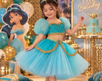 May include: A two-piece turquoise costume featuring a sequined crop top with puff sleeves and a matching tulle skirt. The outfit is adorned with gold trim, decorative blue gems, and a coordinating headband. The set includes a gold-toned waist belt.