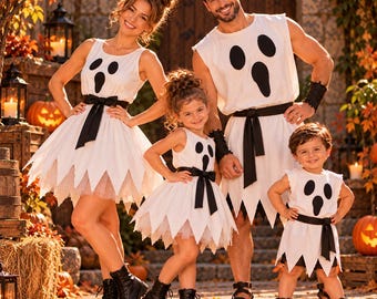 Puede incluir: Una familia viste disfraces de fantasma blancos a juego con estampados de caras de fantasma negras, fajas negras en la cintura y faldas o túnicas con dobladillo dentado. Los trajes son sin mangas e incluyen una capa de tul blanco bajo las faldas.