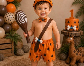 May include: A prehistoric-themed costume set consisting of orange shorts with black triangles, a matching bow tie, a brown sash with a white bone accent, and an orange beret with black triangles and a white pom-pom, paired with a brown club prop.