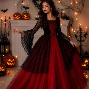 May include: A floor-length gown featuring a deep red velvet bodice with a square neckline and a high, stiffened collar. The long, flared sleeves are made of black lace, matching the black lace overlay that drapes over the full, layered red tulle skirt.