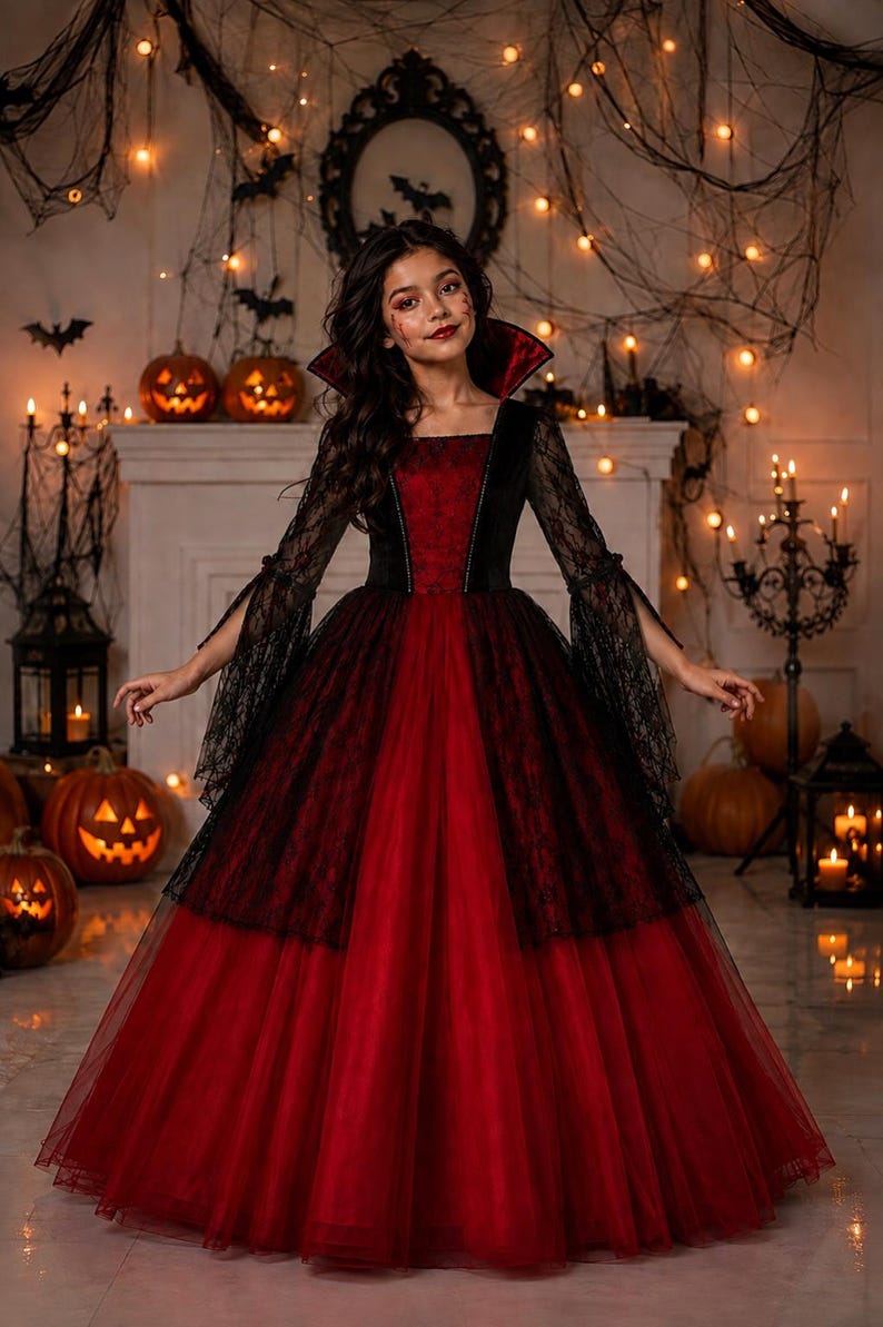 May include: A floor-length gown featuring a deep red bodice and a voluminous skirt made of layered red tulle. The dress includes long, flared black lace sleeves and a high, stiffened collar with a red interior lining, creating a dramatic silhouette.