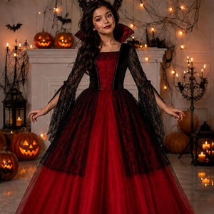 May include: A floor-length gown featuring a deep red bodice and a voluminous skirt made of layered red tulle. The dress includes long, flared black lace sleeves and a high, stiffened collar with a red interior lining, creating a dramatic silhouette.