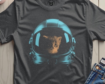 May include: Dark gray t-shirt featuring a kitten wearing a blue astronaut helmet. The kitten's face is visible inside the helmet. The shirt has a crew neck and short sleeves. The brand logo is visible on the upper back of the shirt.