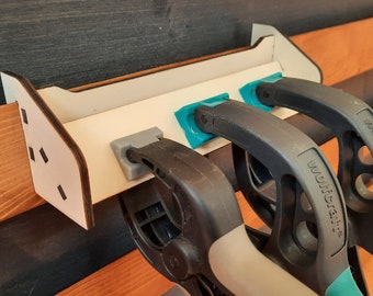 May include: A white wooden wall-mounted organizer with three black and teal clamps. The clamps are labeled "Wolfcraft".
