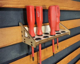 May include: A wooden wall-mounted screwdriver holder with five red screwdrivers. The holder has a white background and eight holes for the screwdrivers.