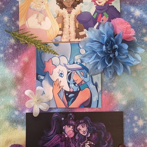 May include: Three different illustrated cards featuring anime-style characters. The first card features three characters with brown, blonde, and red hair. The second card features a blue-haired character with a white creature. The third card features two characters with long black hair.