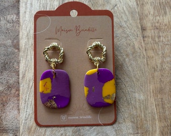 May include: Purple and yellow abstract earrings with gold accents. The earrings are on a card with the text "Maison Brindille".