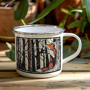 May include: White enamel mug with a black and white illustration of a fox in a forest. The fox is looking to the right and has a red and orange coat. The mug has a silver rim and handle.