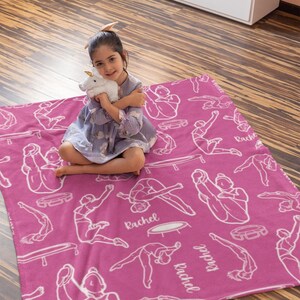 May include: Pink fleece blanket with a white outline of a person doing a gymnastics move on a trampoline. The blanket has the name "Rachel" printed on it multiple times.