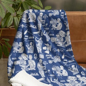 May include: A blue fleece blanket with a white pattern of film cameras, microphones, and the word "JACK" repeated throughout.