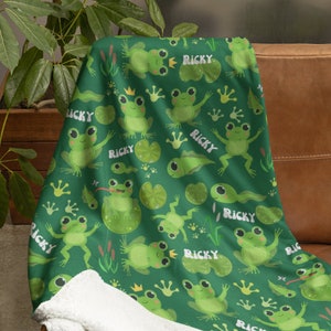 May include: Green fleece blanket with a repeating pattern of frogs, lily pads, and the name "Ricky".