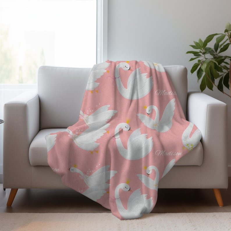 May include: Pink fleece throw blanket with a white swan pattern and the name "Madison" repeated throughout.
