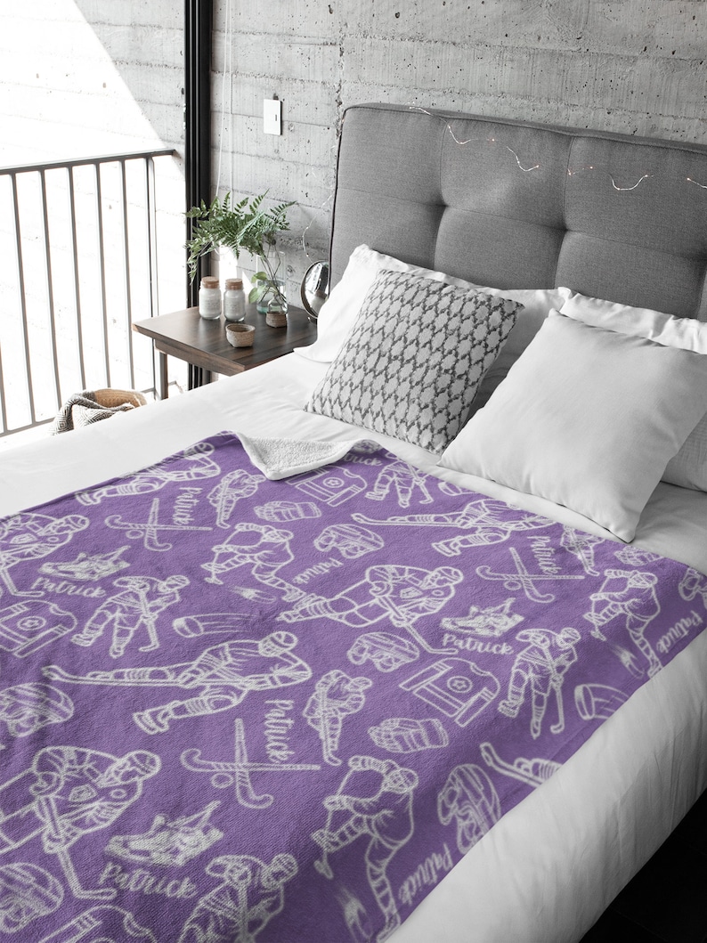 Pu&ograve; includere: Coperta in pile viola con un motivo di giocatore di hockey bianco. La coperta presenta un motivo ripetuto di giocatori di hockey, puck, bastoni e il nome "Patrick".