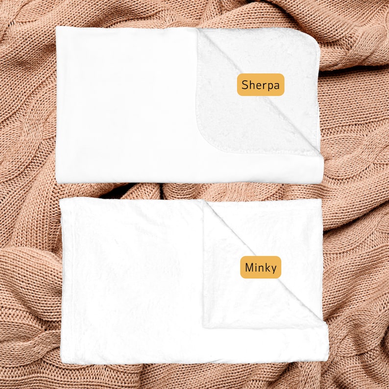 May include: Two white blankets, one labeled "Sherpa" and the other labeled "Minky", are displayed on a brown knitted surface.