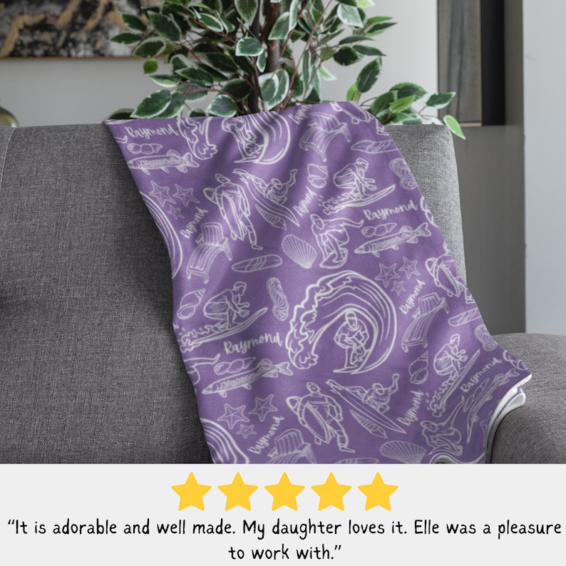 May include: Purple fleece blanket with a white repeating pattern of a surfer, waves, fish, seashells, and the name "Raymond".