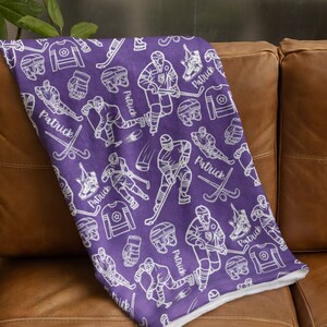 Pu&ograve; includere: Coperta in pile viola con un motivo bianco a tema hockey. Il motivo include giocatori di hockey, puck, bastoni e il nome "Patrick" ripetuto in tutto.