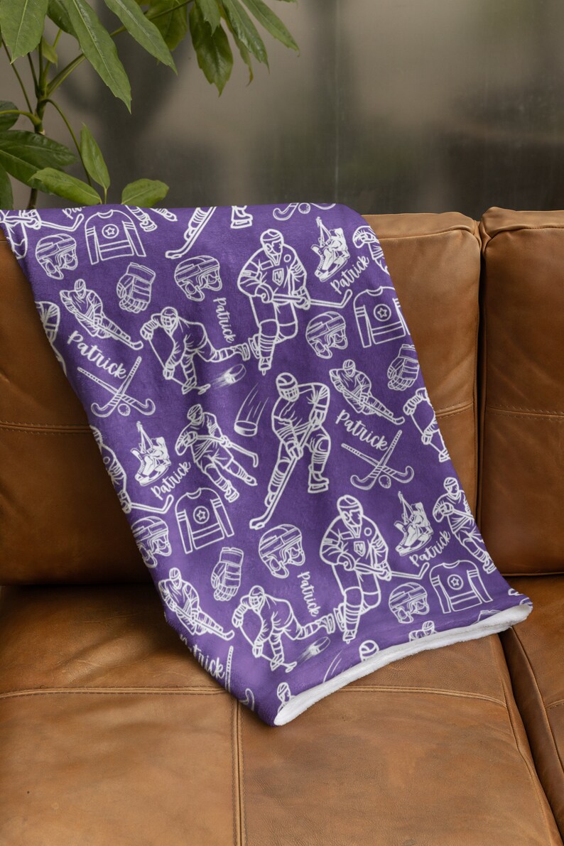 Pu&ograve; includere: Coperta in pile viola con un motivo bianco a tema hockey. Il motivo include giocatori di hockey, puck, bastoni e il nome "Patrick" ripetuto in tutto.