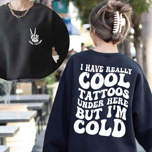 May include: Black sweatshirt with white text that reads "I have really cool tattoos under here but I'm cold".