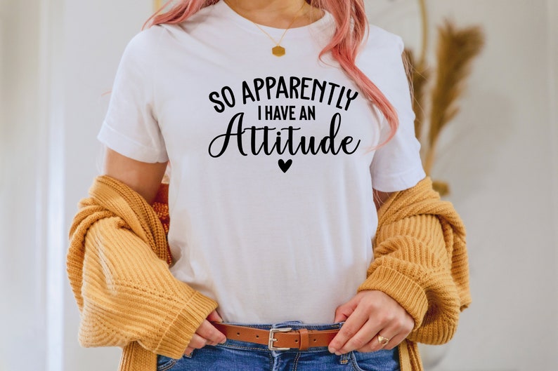 May include: White t-shirt with black text that reads "So Apparently I Have An Attitude" with a small black heart below the text.