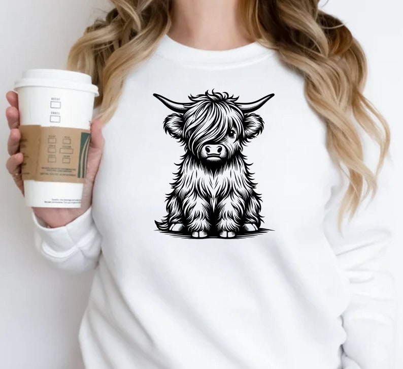K&ouml;nnte beinhalten: Wei&szlig;es Sweatshirt mit einer Schwarzwei&szlig;-Illustration einer Highland-Kuh mit langem Fell und H&ouml;rnern.