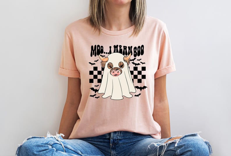 May include: A pink t-shirt with a black and white checkered pattern and a ghost cow with the text "Moo... I mean Boo" on it.